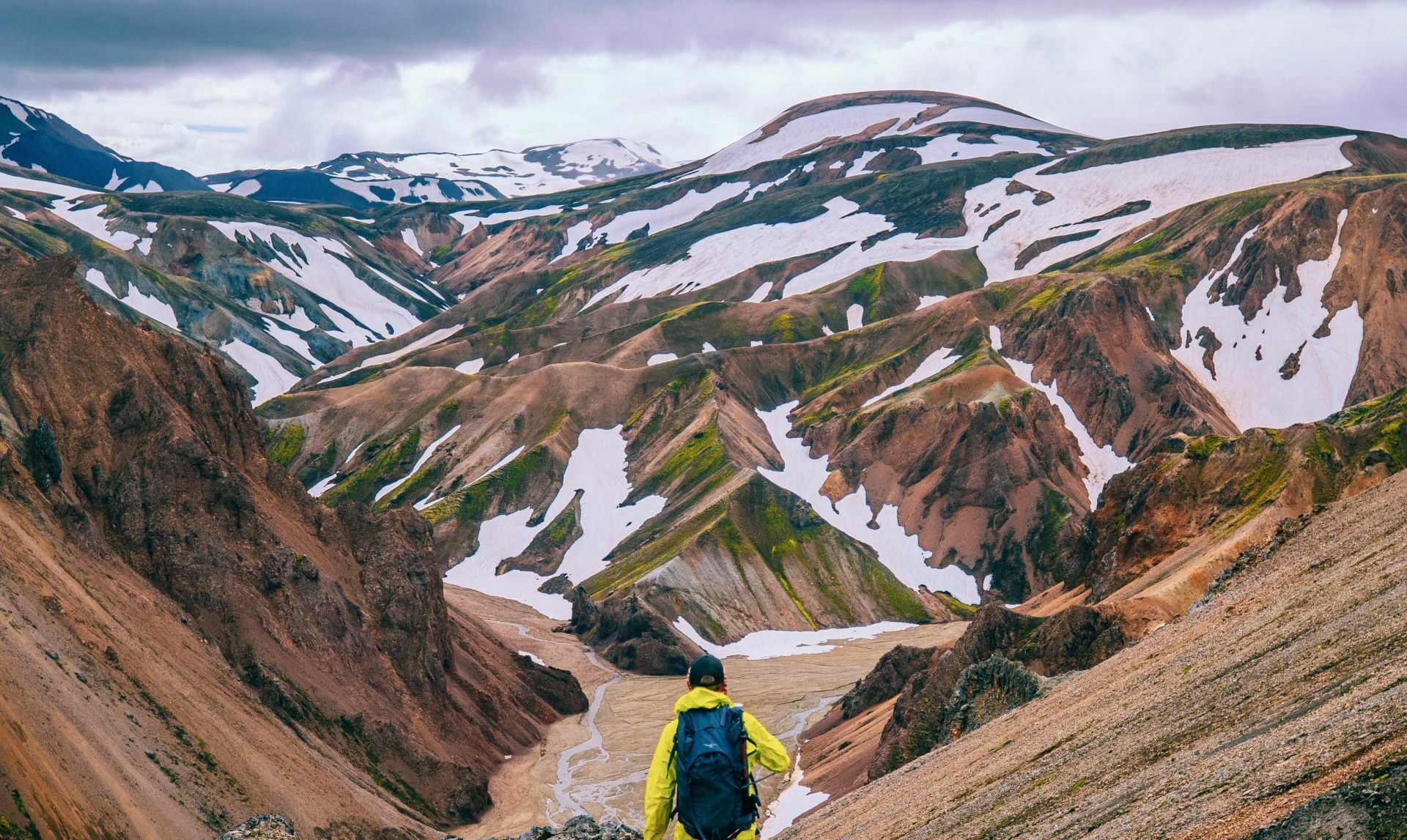 Hiker looking out onto snow-patched mountains in Landmannalaugar