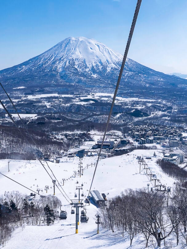 A ski resort with a gondola and a volcano shape mountain in the background.