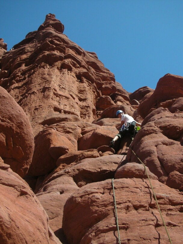 A climber ascending a tower in the Moab region